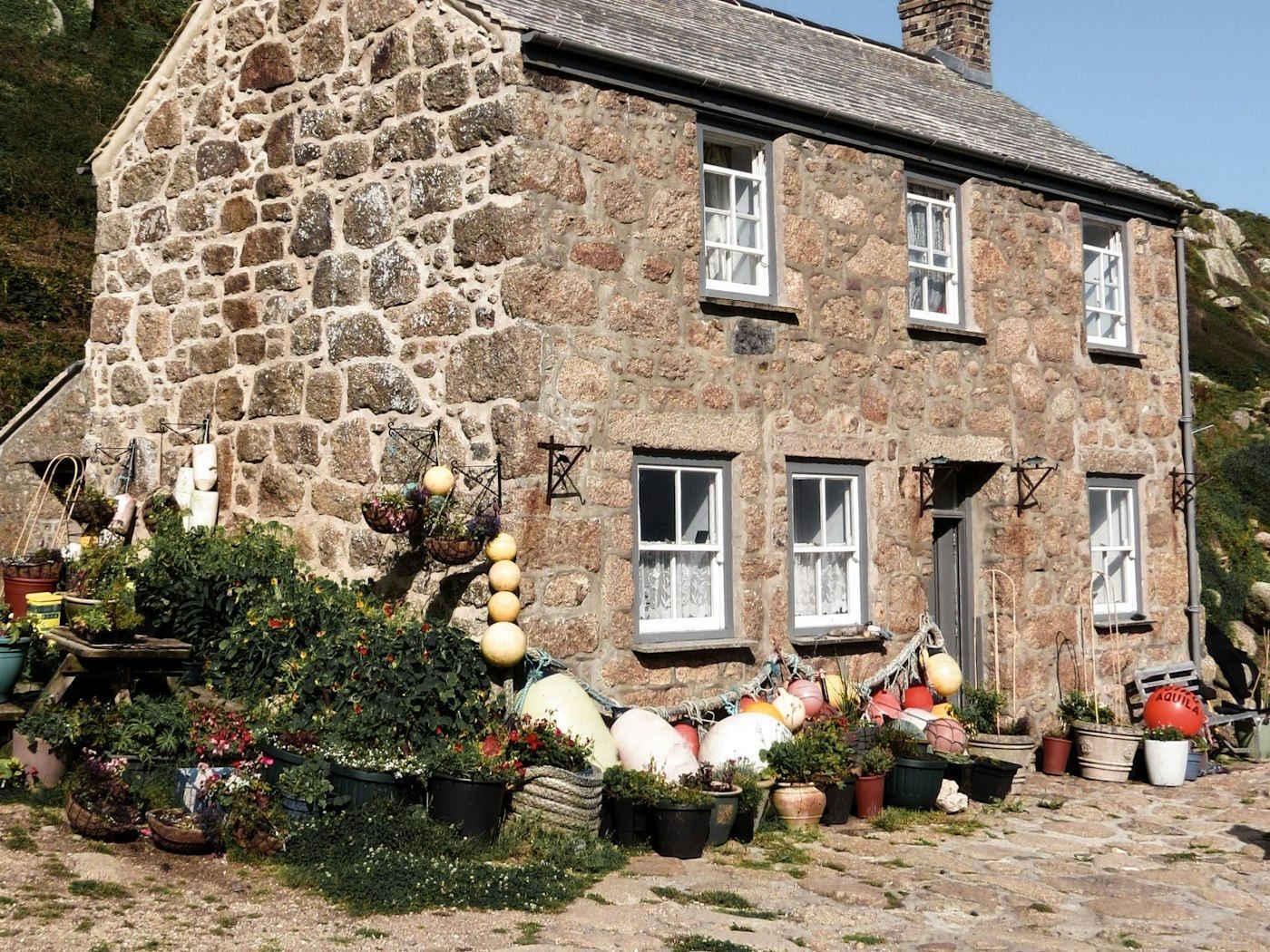 The stone front of the house with flowers along the wall