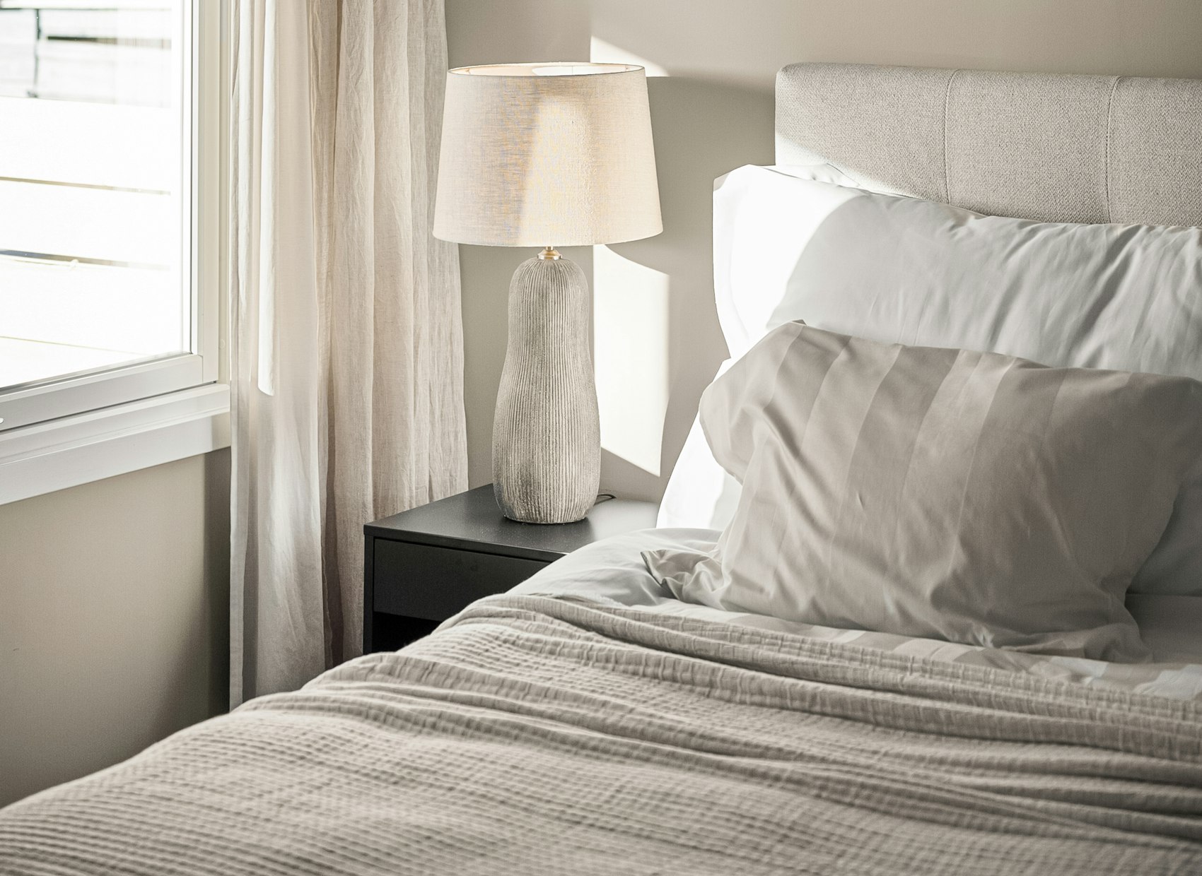 The Harbour Room: a white bed beside a bright window with a reading lamp