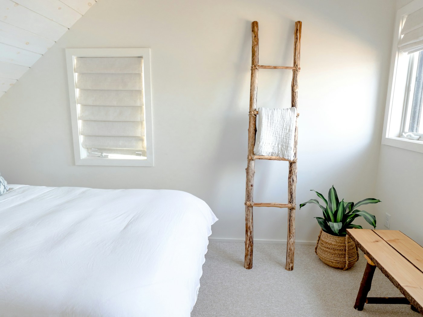 The Lookout: a white bed under the eaves with a driftwood ladder and shuttered window